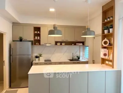 Modern kitchen with sleek cabinets and stainless steel fridge in open layout design.