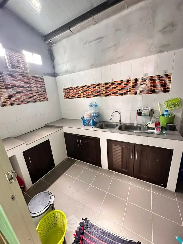 Cozy kitchen with dual sink and tiled backsplash, featuring ample counter space and modern cabinetry.