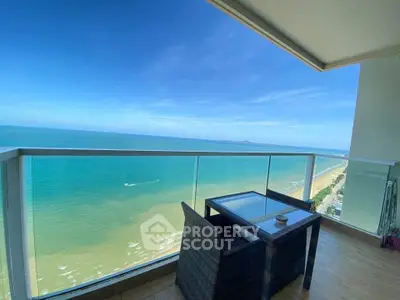 Stunning ocean view from a modern balcony with glass railing and cozy seating area.