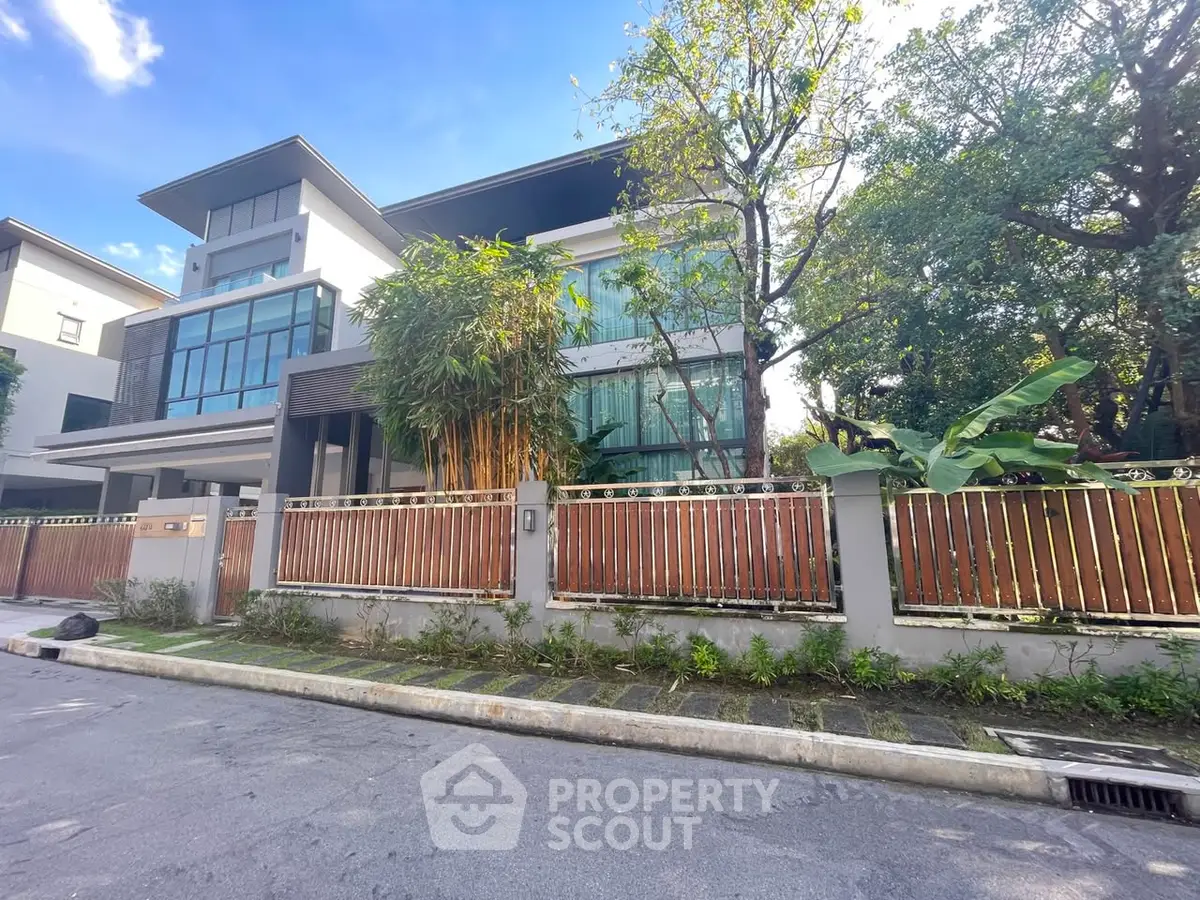 Luxurious modern house with large windows and lush greenery in a serene neighborhood.