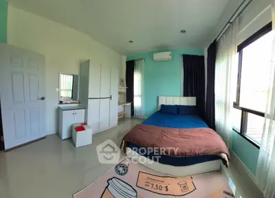 Spacious bedroom with modern decor and large windows offering natural light