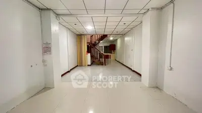 Spacious interior with tiled flooring and staircase, ideal for customization.