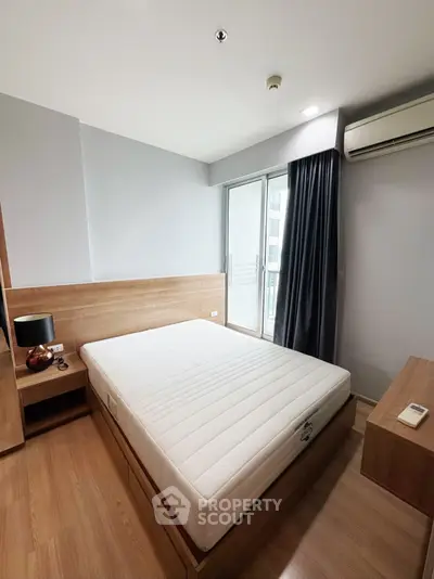 Modern bedroom with wooden flooring and balcony access in a stylish apartment.