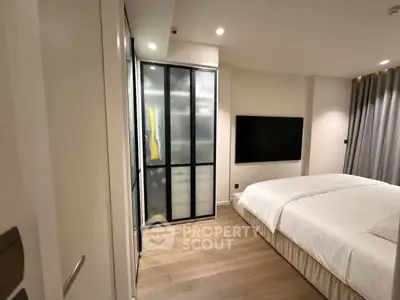 Modern bedroom with sleek design, featuring a large bed, wooden flooring, and a wall-mounted TV for ultimate comfort.