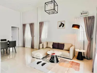 Spacious modern living room with elegant decor and dining area, featuring a stylish chandelier and cozy seating.