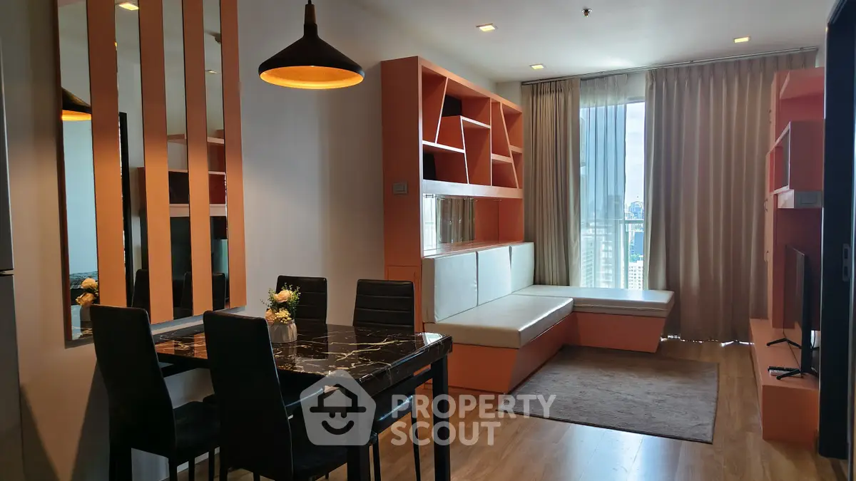 Modern living room with stylish furniture and city view, featuring a cozy dining area and ample natural light.