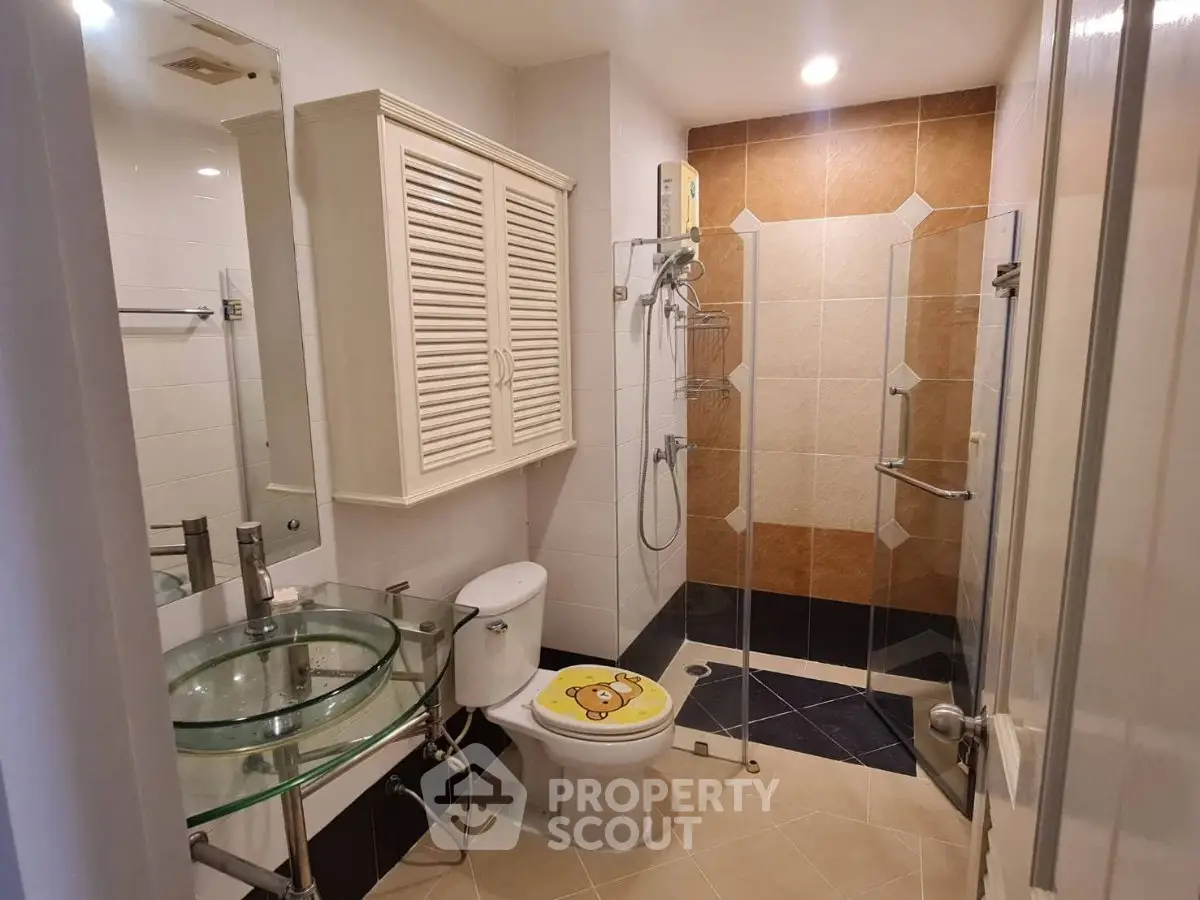 Modern bathroom with glass sink and shower enclosure in stylish apartment.