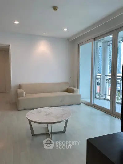 Spacious living room with modern sofa and large windows offering city view.