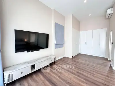 Spacious modern living room with sleek TV setup and ample storage space.