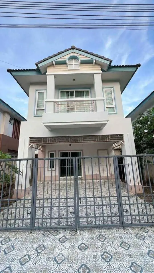 Charming two-story house with a gated entrance and tiled front yard, perfect for family living.