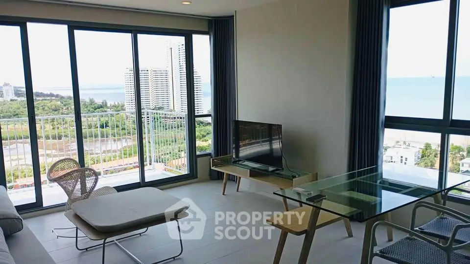 Modern living room with stunning ocean view and floor-to-ceiling windows in a high-rise apartment.