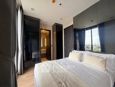 Modern bedroom with large windows and city view, featuring sleek design and cozy bedding.