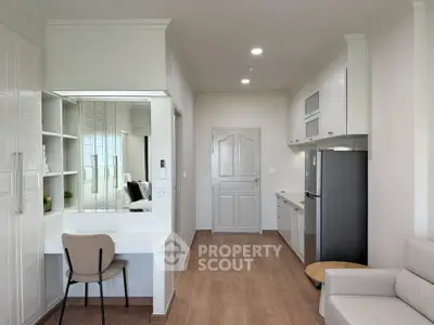 Modern apartment interior with sleek kitchen and cozy living area, featuring stylish furniture and bright lighting.