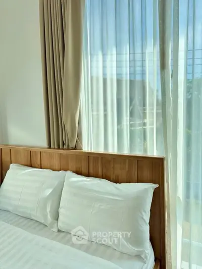 Bright and cozy bedroom with wooden headboard and sheer curtains