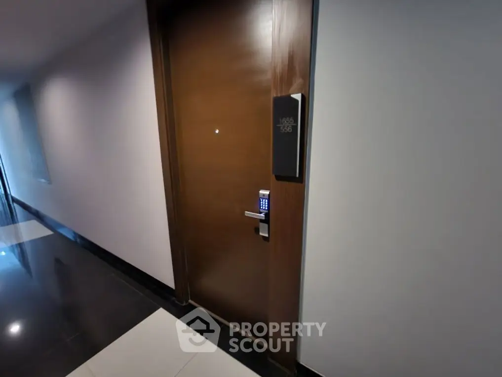 Modern apartment entrance with digital lock and sleek design in a well-lit corridor.