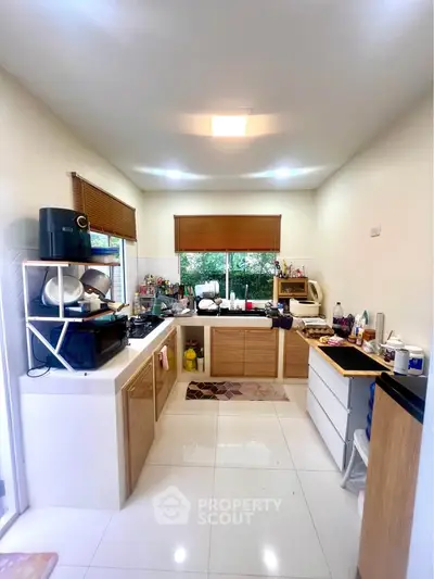 Modern kitchen with sleek cabinetry and ample natural light, featuring a closed layout and contemporary appliances.