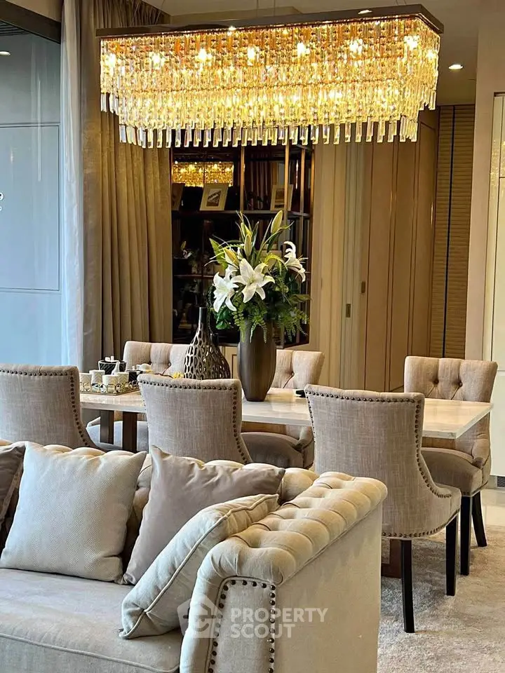 Luxurious living room with elegant chandelier and plush seating in modern apartment.