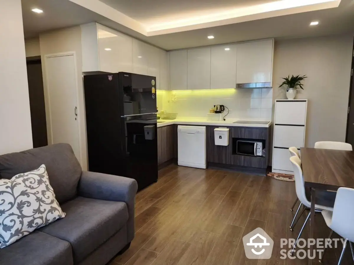 Modern kitchen with sleek cabinets and cozy dining area in open layout apartment.