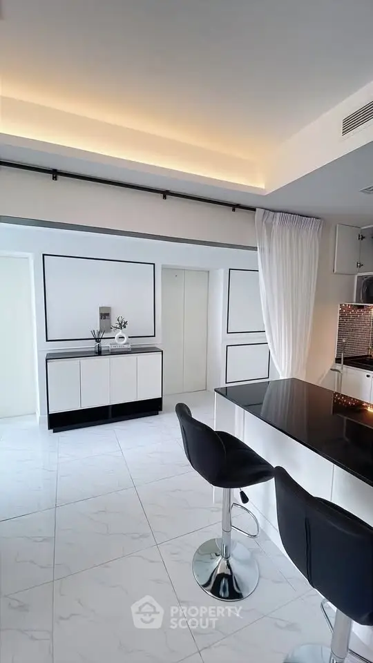 Modern kitchen with sleek black and white design, featuring a breakfast bar and stylish bar stools.