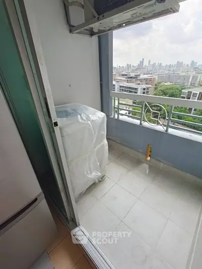 High-rise balcony with city skyline view and washing machine setup.
