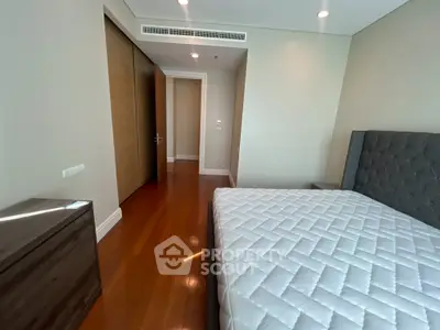 Spacious bedroom with modern design and wooden flooring in luxury apartment.