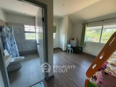 Spacious bedroom with attached bathroom and large windows for natural light.