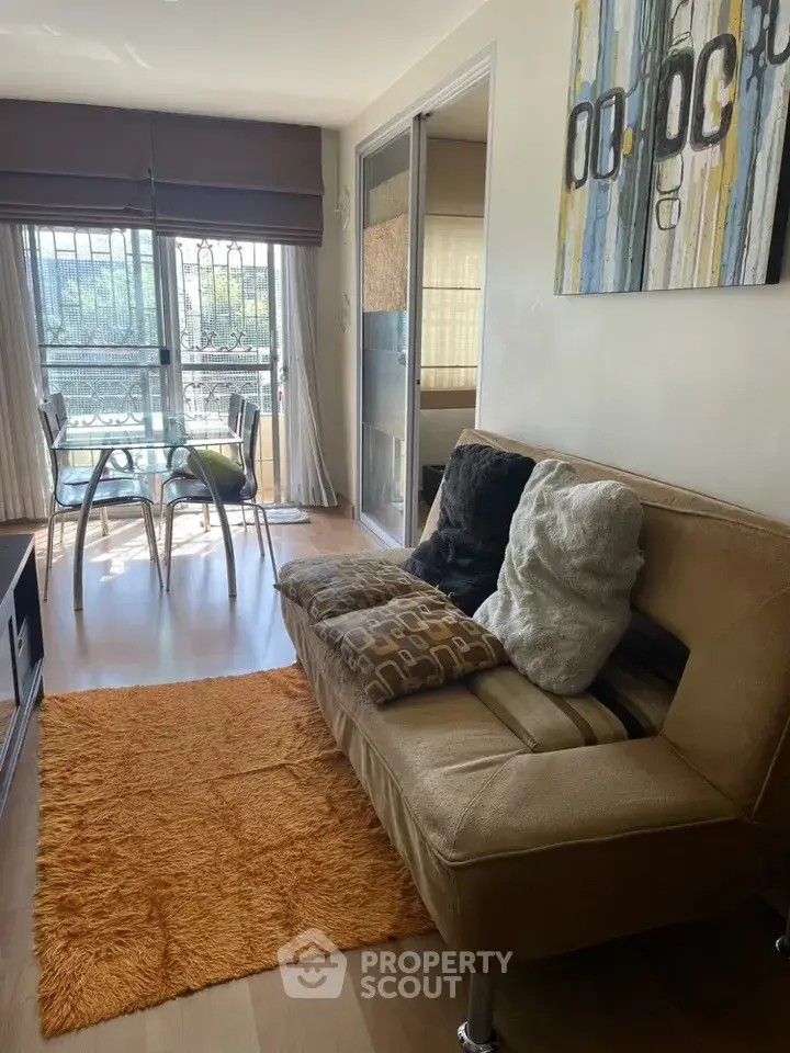 Cozy living room with modern decor and natural light, featuring a stylish sofa and dining area.