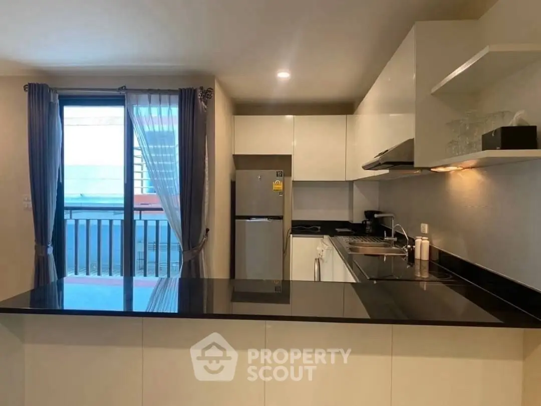 Modern kitchen with sleek design and balcony view, featuring open layout and contemporary appliances.