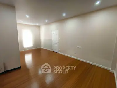 Spacious empty room with wooden flooring and recessed lighting, perfect for customization.