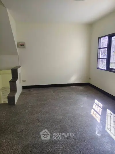 Spacious empty room with large window and natural light, perfect for customization.