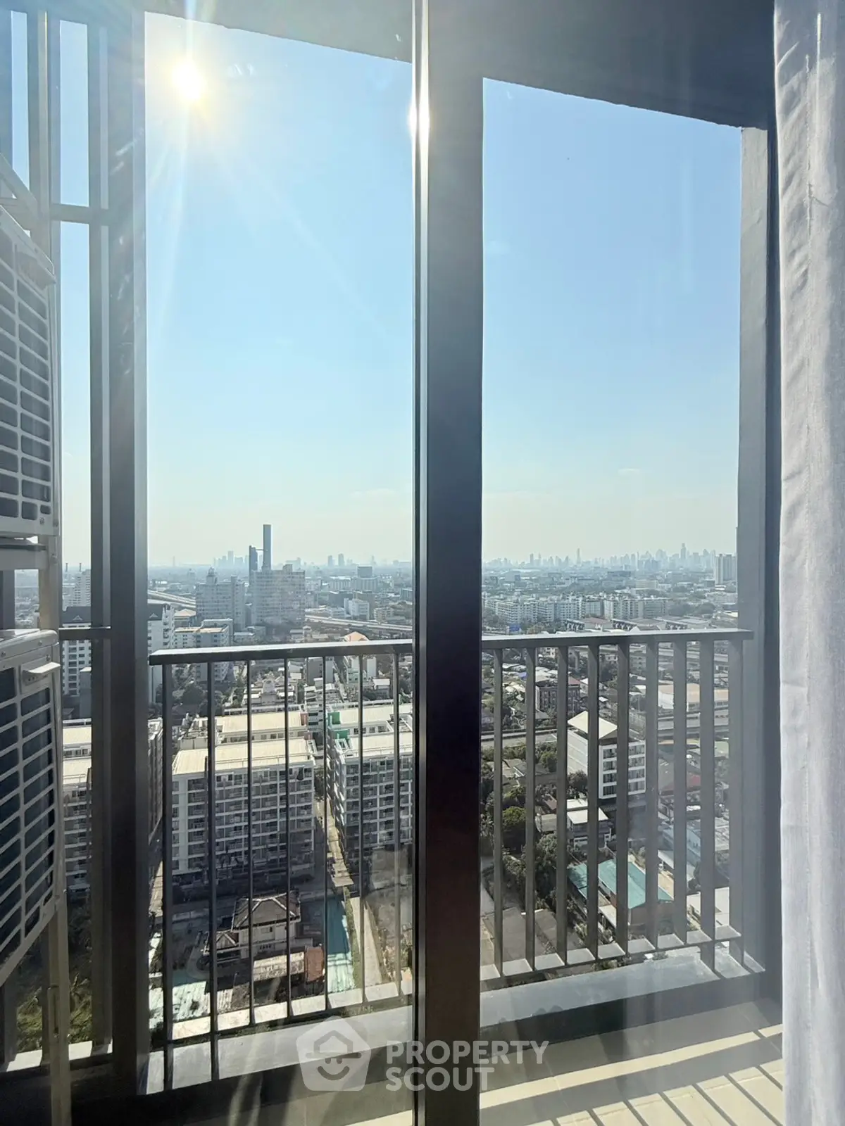 Stunning high-rise balcony view with cityscape and clear blue sky