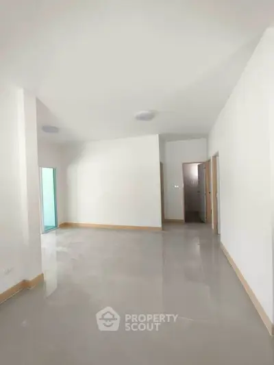 Spacious empty living room with modern tile flooring and natural light.