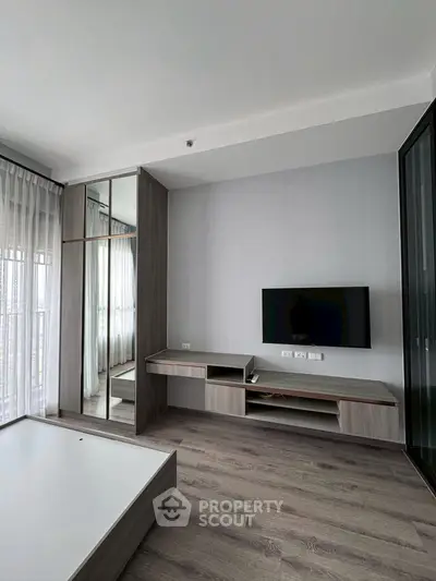 Modern living room with sleek TV unit and large windows for natural light