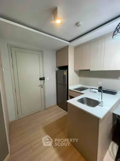 Modern kitchen with sleek cabinetry and stainless steel fridge in a compact layout.