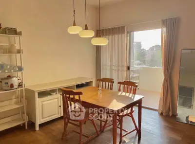 Charming dining area with wooden table and chairs, leading to a sunlit balcony.