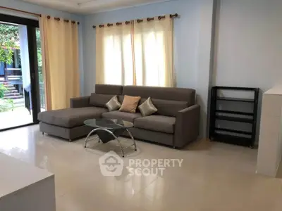 Spacious living room with modern sofa and glass coffee table, perfect for relaxation and entertaining.