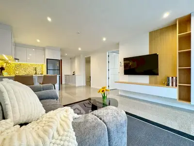Modern living room with open kitchen, stylish decor, and cozy seating area.