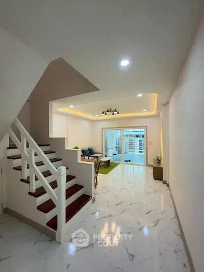 Spacious modern living room with elegant staircase and marble flooring