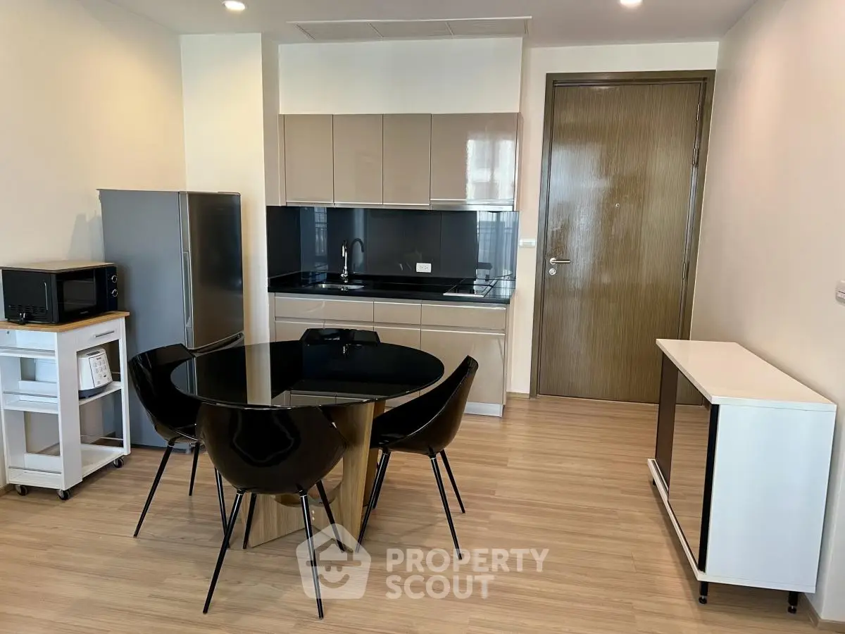 Modern kitchen with sleek black dining set and stainless steel appliances in a stylish apartment.