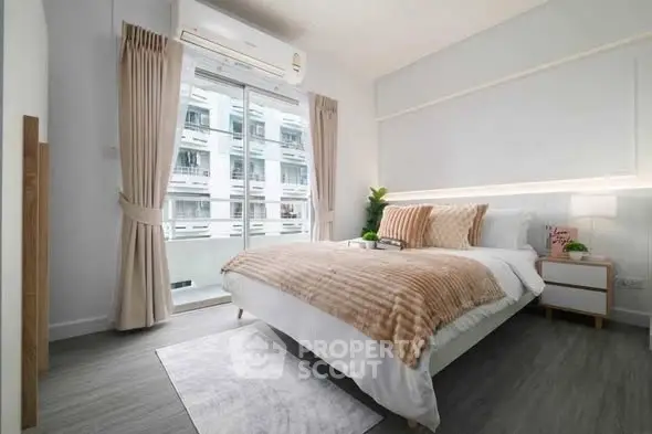 Modern bedroom with stylish decor and large window offering natural light in a contemporary apartment.