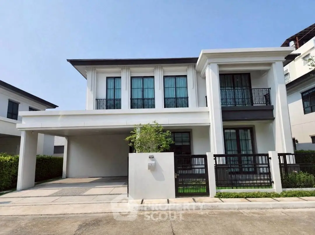 Elegant modern two-story house with large windows and gated driveway in a serene neighborhood.