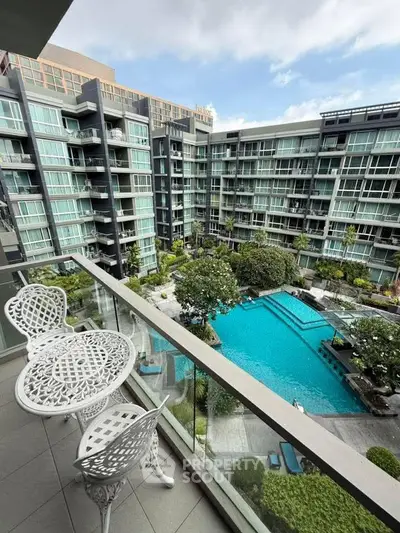 Luxurious condo balcony overlooking a stunning pool and modern building facade.