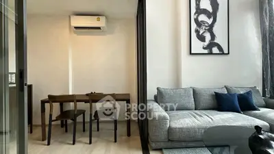 Modern living room with stylish decor and dining area, featuring a cozy gray sofa and elegant artwork.