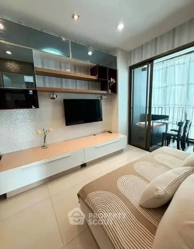 Modern living room with stylish decor and balcony access, featuring a sleek entertainment unit and cozy seating.
