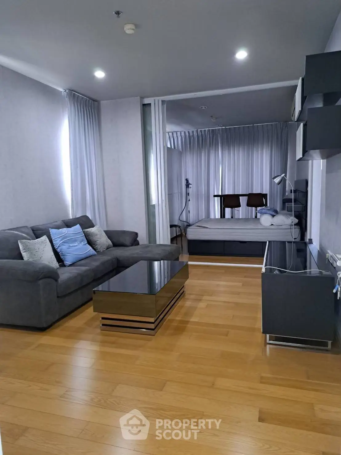 Modern studio apartment with stylish living area and cozy bedroom, featuring sleek furniture and wooden flooring.