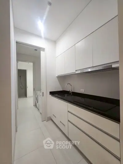 Modern kitchen with sleek white cabinetry and black countertop