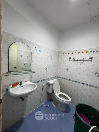 Compact bathroom with tiled walls, mirror, and basic fixtures.