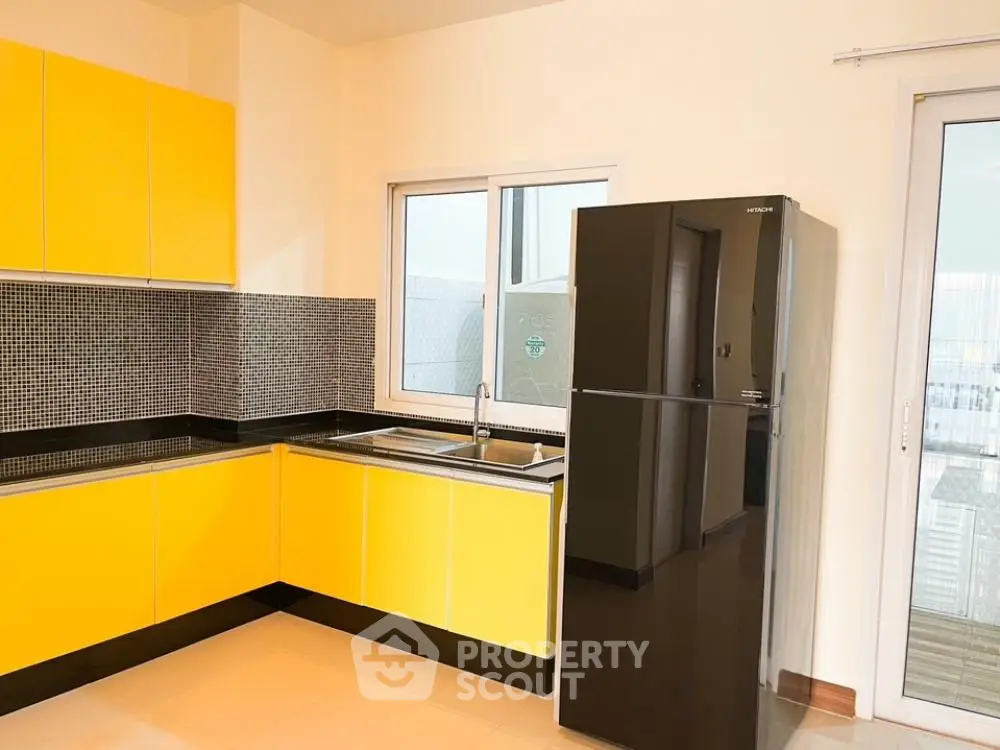 Bright kitchen with vibrant yellow cabinetry, modern appliances, and ample natural light, perfect for culinary enthusiasts.