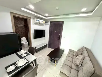 Modern living room with cozy sofa and dining area, featuring sleek TV setup.