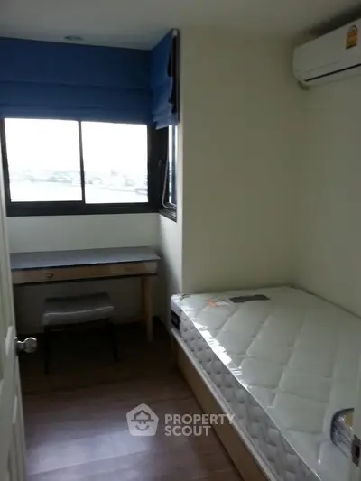 Cozy bedroom with natural light, featuring a single bed and study desk, perfect for a compact living space.